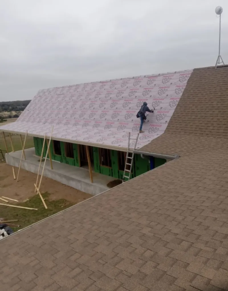 Worker preparing underlayment for a metal roof installation in Northfield